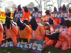 Participants in a rally sponsored by The World Can't Wait are dressed as hooded detainees and holding WCW signs in Upper Senate Park on January 4, 2007. (Ben Schumin/Wikimedia Commons)