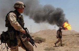 US soldiers near a burning oil well in the Rumaylah oil fields in southern Iraq, April 2, 2003. (Arlo K. Abrahamson/US Navy)